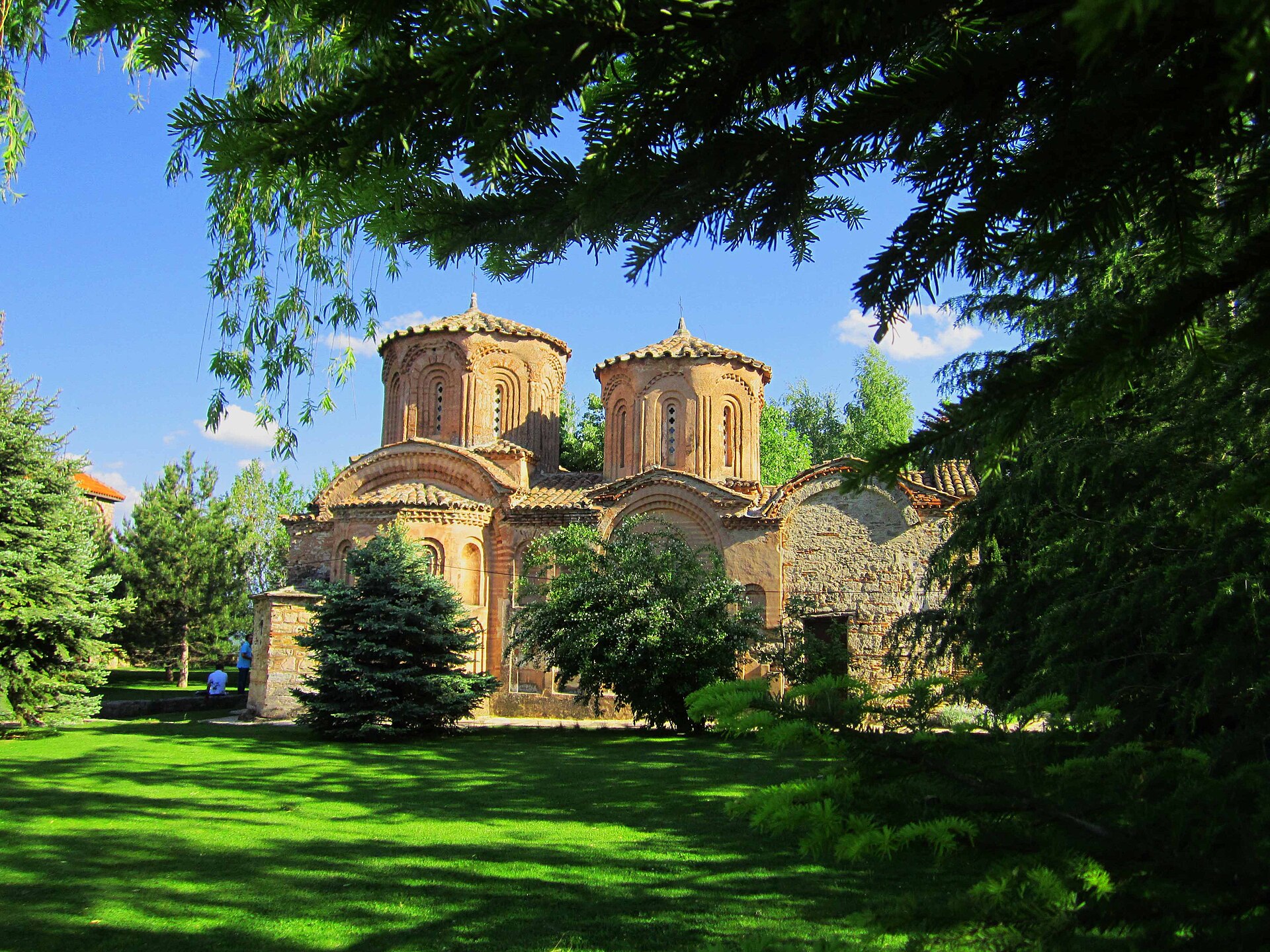 Veljusa Monastery framed by trees and green lawns.