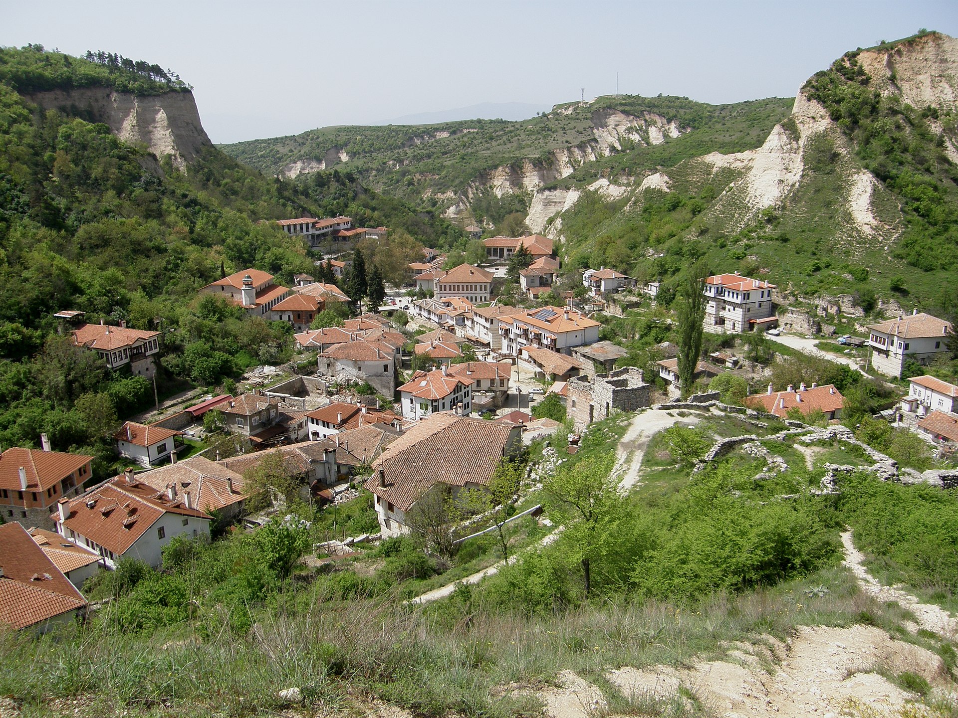 Red-roofed houses in Melnik beneath pale sandstone hills.
